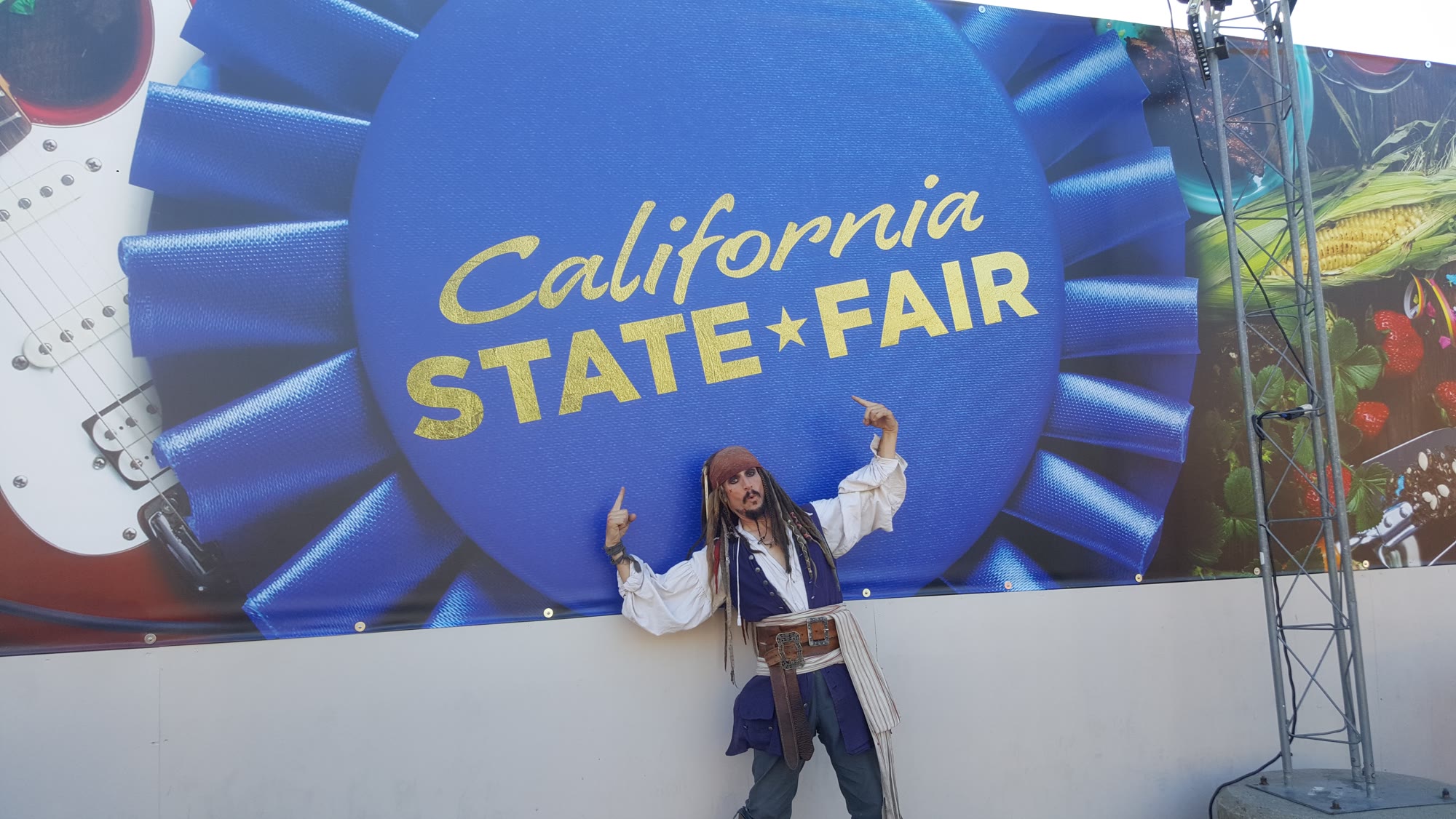 Capt'n Jack Spareribs pointing up at the California State Fair sign.