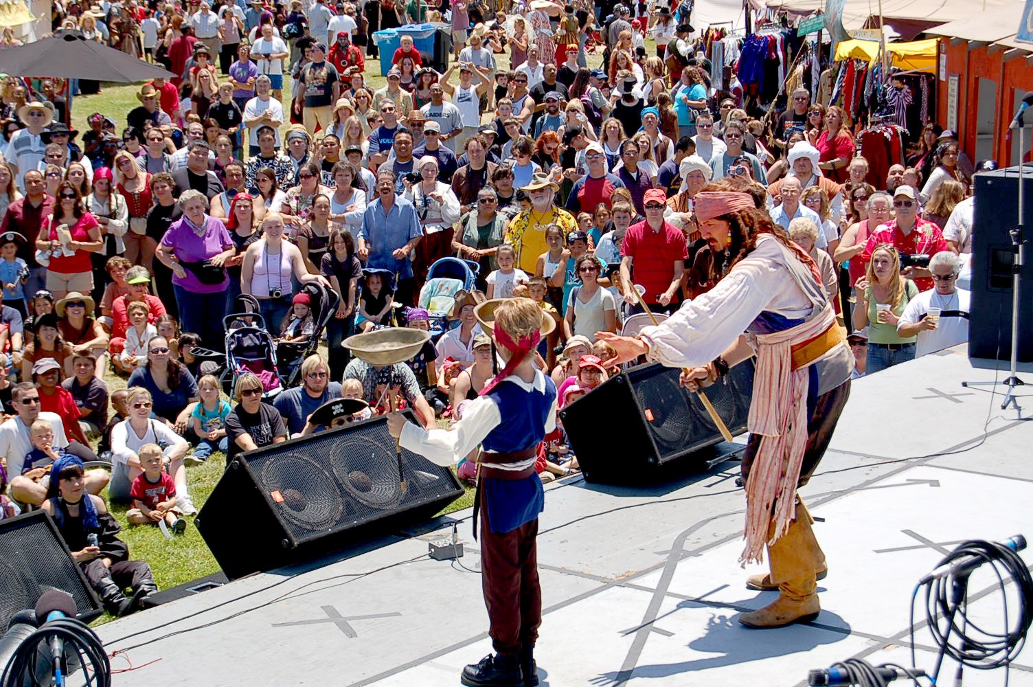 Jack and a fellow performer working the stage in front of a packed crowd of mostly adults, watching closely, cameras up.